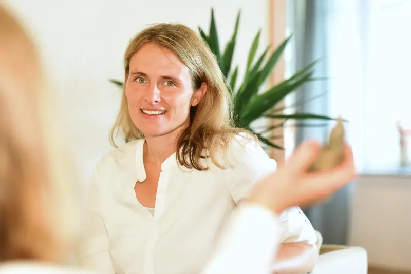 Coachin im Einzelgespräch während eines Kommunikationstrainings, sitzt entspannt im Beratungsraum und hört einer Teilnehmerin aufmerksam zu