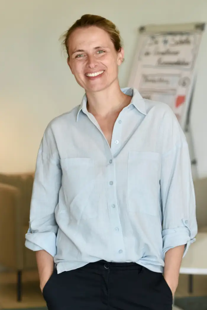 Alt-Tag Vorschlag mit Name und Firmenname:  Nicole Tepaße von Rede Klartext steht entspannt im Seminarraum vor Flipchart und begleitet Kommunikationstraining für Fachkräfte